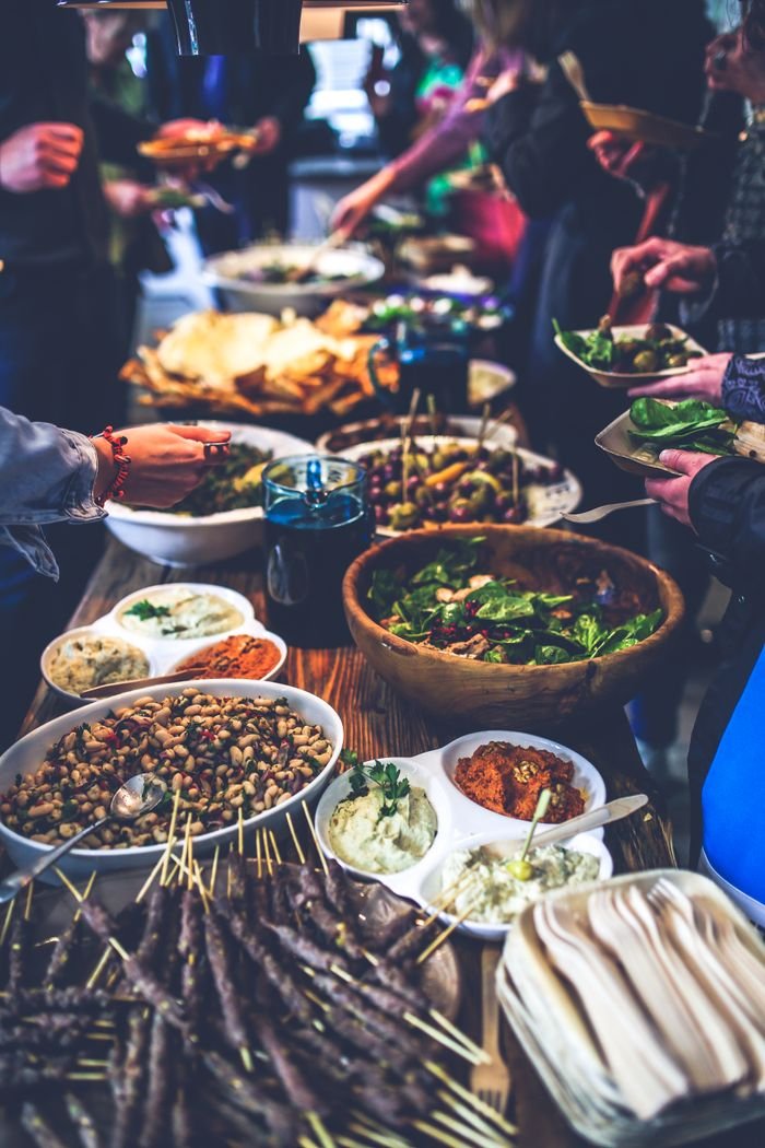 A vibrant buffet spread with salads, skewers, and dips at a lively indoor gathering.