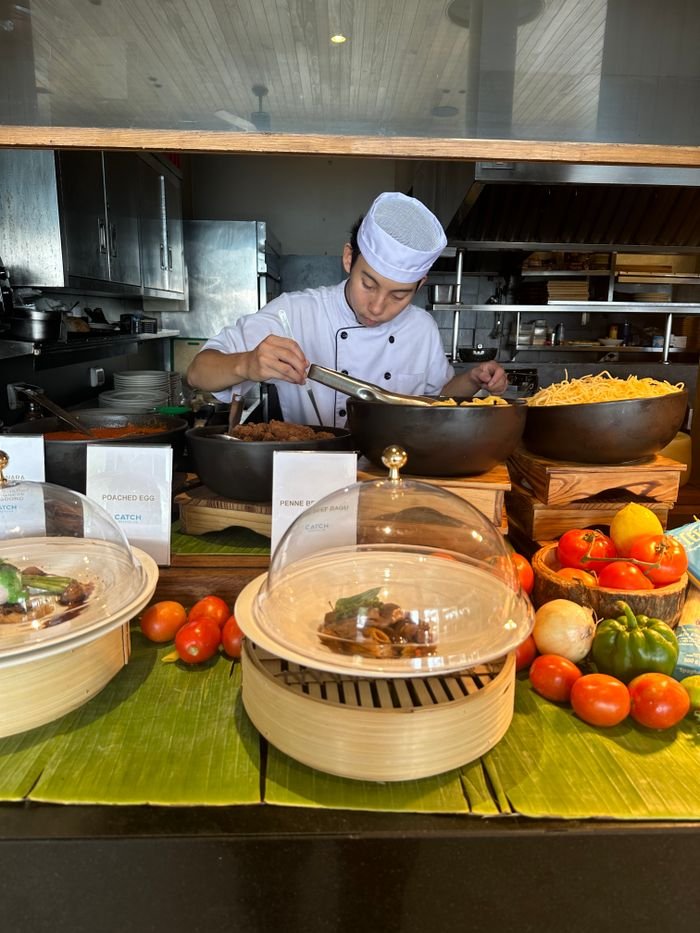 Culinary scene of a chef cooking pasta with fresh ingredients in an open kitchen.